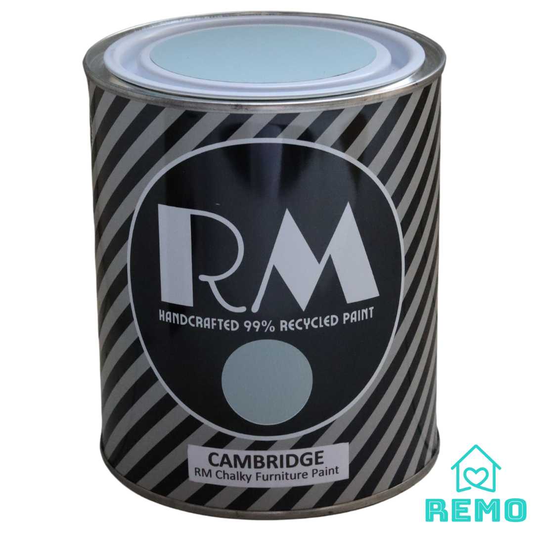 Angled view of a tone of Cambridge RM Furniture Paint. Shows a striped tin with Art Deco style RM letters. the name CAMBRIDGE and a painted sticker on the front and on the top of the tin lid.